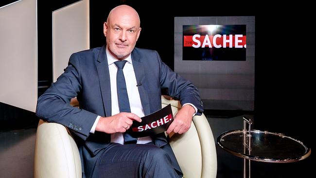 Woflgang Geier sitzt in einem Fauteuil neben einem Glastisch im "zur SACHE"-Studio