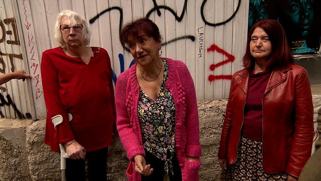 Drei ältere Frauen vor einer Graffiti-Wand.
