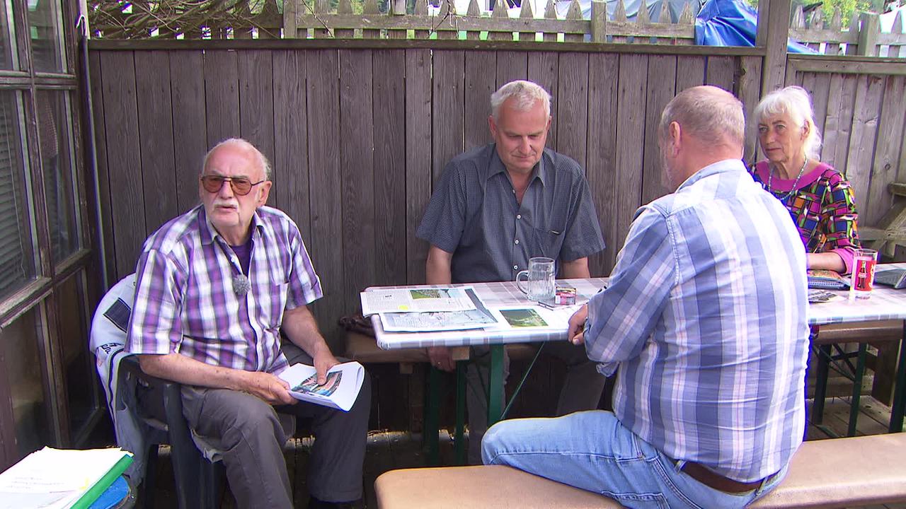 Drei ältere Herren und eine Frau an einem Biertisch im Schanigarten.