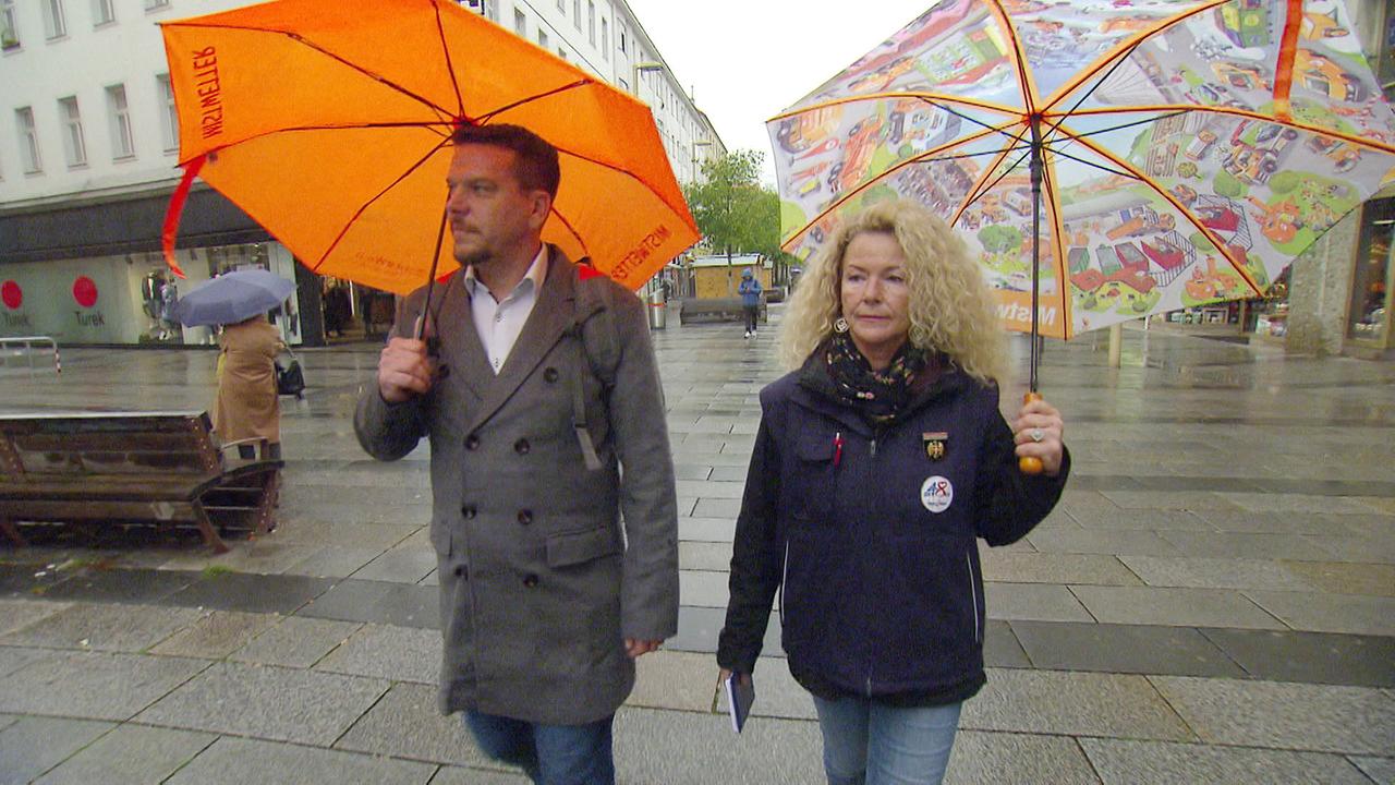 Ein Mann und eine Frau mit Regenschirm auf einer Einkaufsstrasse