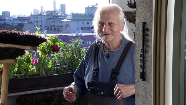 Herr Gottfried mit einem Lächeln im Gesicht auf seinem Balkon 