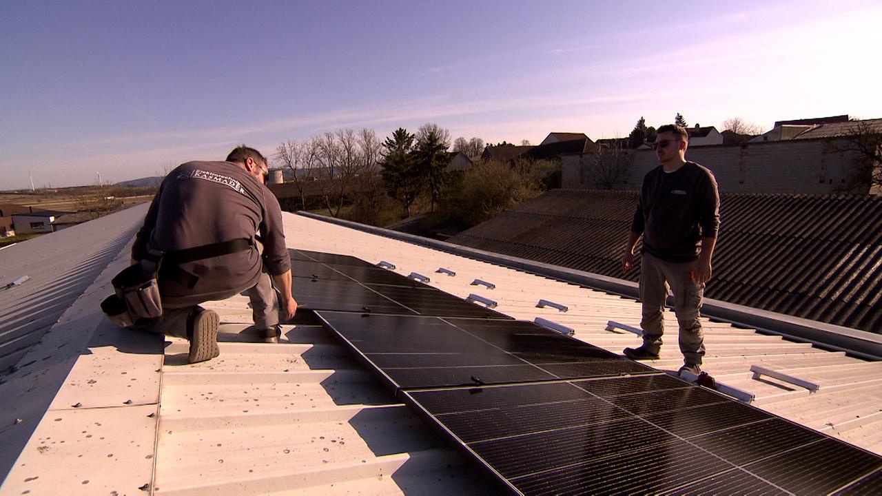 Eliktriker arbeiten auf einem Dach bei Sonnenschein.