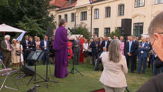 Botschafterin Salome Meyer steht auf einem Podest mit Kunstrasen vor den Gästen