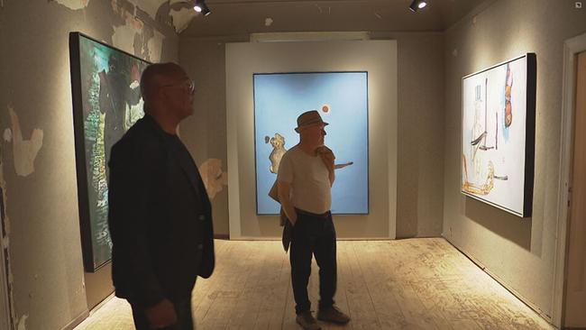Besucher sehen sich Gemälde der Ausstellung an 