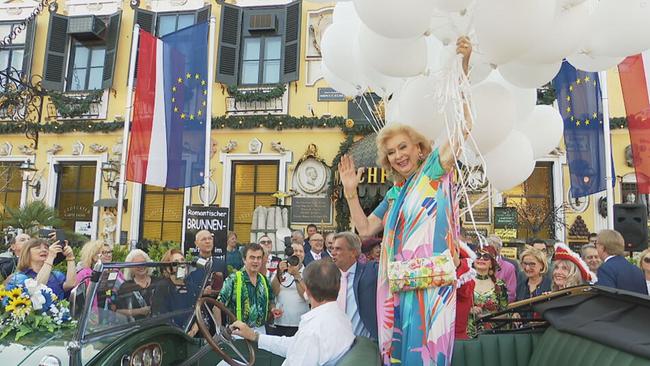Birgit Sarata steht mit Luftballons in der Hand in einem Oldtimer vor dem Marchfelderhof