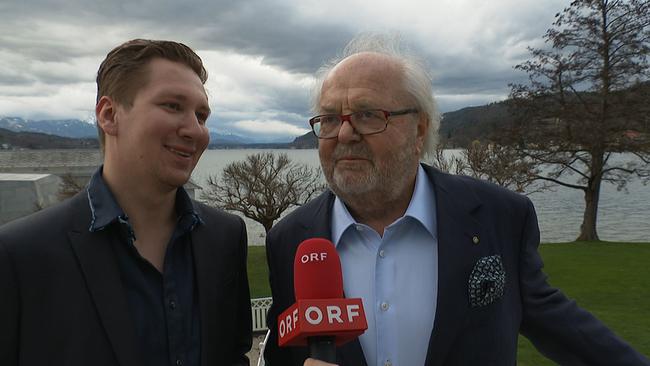 Clemens Trischler steht neben  Hans-Werner Frömmel beim Interview. Im Hintergrund der Wörthersee