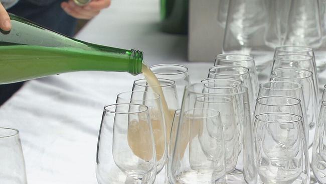 Gläser stehen auf einem Tisch, Sturm wird aus einer Flasche eingeschänkt. 
