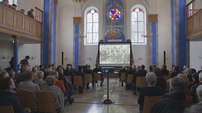 Menschen sehen sich die Filmpremiere in einer Synagoge an