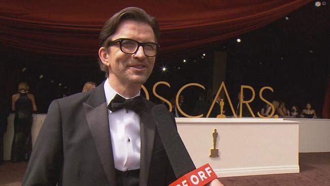 Modeschöpfer Emil Gampe am weißen Teppich, hinter ihm der goldene Oscar Schriftzug