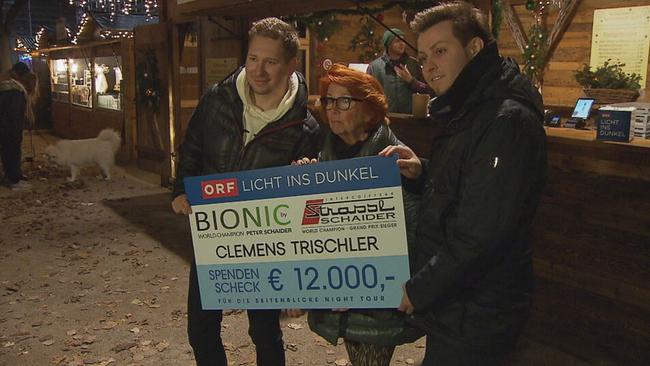 Clemens Trischler, Ingrid Klingohr und Peter Schaider halten einen Karton-Scheck mit einer Summe von 12.000€ in die Kameras