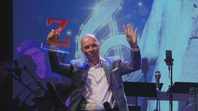 Peter Legat hält den Award in Form eines "Z" ins Publikum 