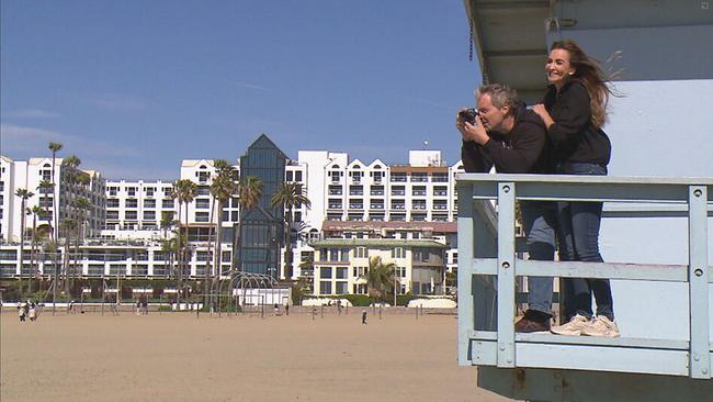 Manfred Baumann macht am Strand aus einem Bademeisterwachturm ein Foto vom Strand, seine Frau Nelly steht hinter ihm