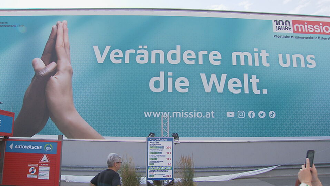 200 Quadratmeter großes Plakat von Missio Österreich auf dem man zwei Hände unterschiedlicher Hautfarbe, die zum Gebet gefaltet sind sieht und auf dem steht: Verändere mit uns die Welt