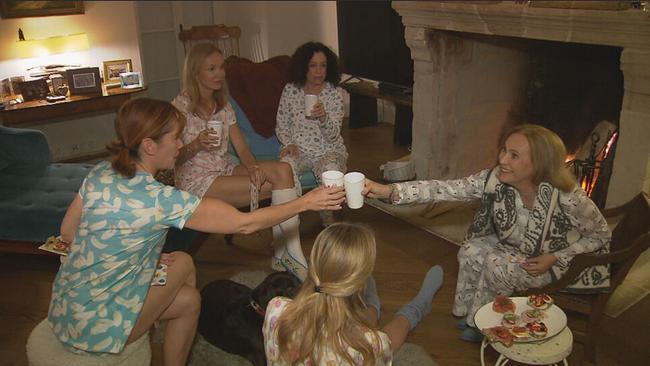 Frauen sitzen in Pyjamas in einem Kreis und stoßen mit Alexandra Hilverth auf ihren Geburtstag an