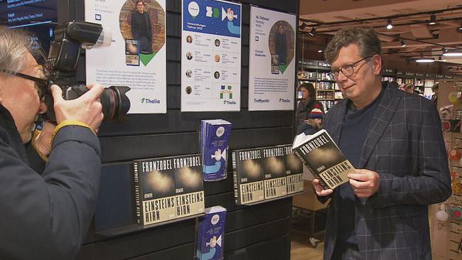 © ORF / Seitenblicke Franzobel posiert mit seinem Buch in der Hand für einen Kameramann