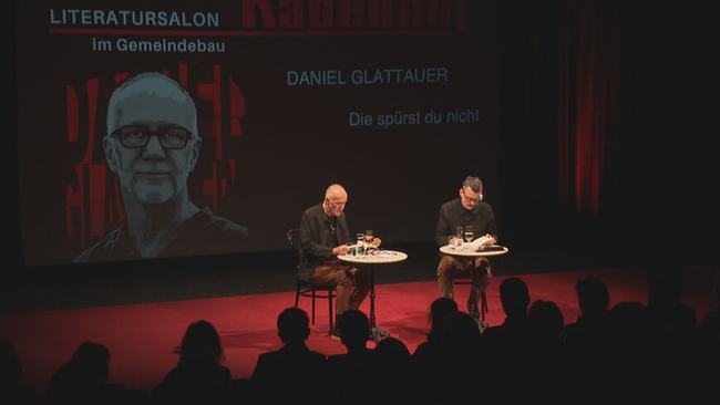 Daniel Glattauer und Manuel Rubey sitzen an Tischen in Wiener Rabenhof