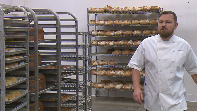 Peter Resch geht in seiner Bäckerei an Stellagen voller Brot vorbei