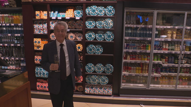 © ORF / Seitenblicke Heinz Fischer vor Supermarktregalen mit einem Glas Wein in der Hand