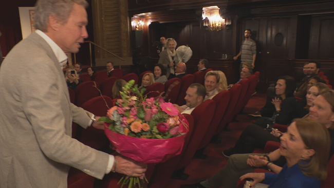 Peter Kraus überreicht seiner Frau einen Blumenstrauß im vollen Kinosaal