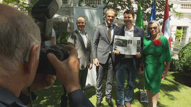 Vier Personen stehen nebeneinander, lächeln in die Kamera und halten eine Zeitschrift in der Hand