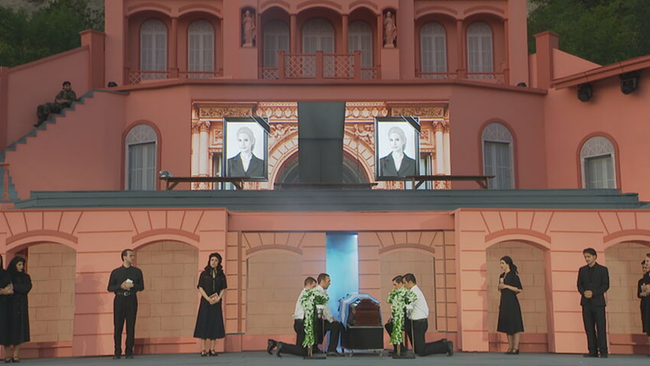 Sarg, Bilder von Evita und Trauernde vor einem roten Gebäude auf der Felsenbühne