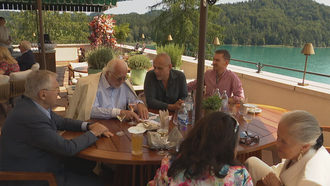 © ORF / Seitenblicke Unternehmerinnen und Unternehmer am Tisch auf der Terrasse sitzend im Gespräch, dahinter der Fuschlsee zu sehen