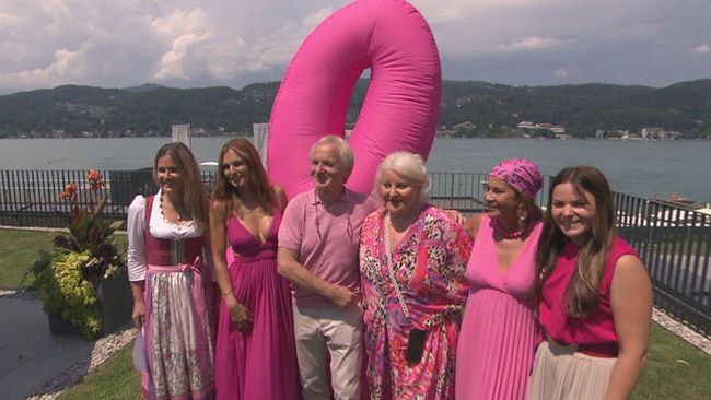 © ORF / Seitenblicke Görgl, Weniger-Assinger, Lichter, Saxx & Präsident der Krebshilfe stehen vor einem pinken Logo für Brustkrebsvorsorge - im Hintergrund der Wörthersee