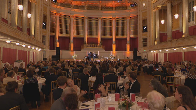 Winer Konzerthaus von innen: Saal ist voll mit gedeckten Tischen und Menschen sitzen & lauschen Musik auf der Bühne