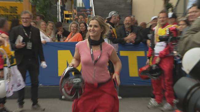 © ORF / Seitenblicke Lizz Görgl im Rennanzug und mit Helm in Hand neben der Rennstrecke laufend