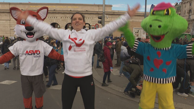 © ORF / Seitenblicke Conny Kreuter und zwei Maskottchen machen Hampelmänner vor der Hofburg in Wien
