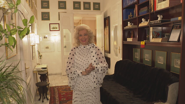 © ORF / Seitenblicke Birigt Sarata steht im Eingangsbereich ihrer Wohnung und strahlt in die Kamera