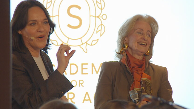 Moderatorin Eva Pölzl und Organisatorin Elisabeht Gürtler stehen gemeinsam auf der Bühne und lachen