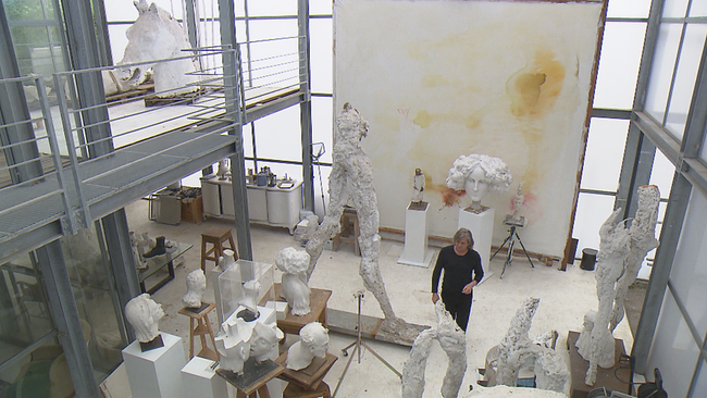 Andjé Pietrzyk zwischen großen, weißen Skulpturen in seinem hohen Atelier 