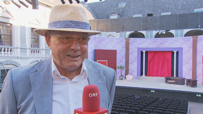 Wolfgang Böck vor der Theaterkulisse im Schloss lachend im Interview