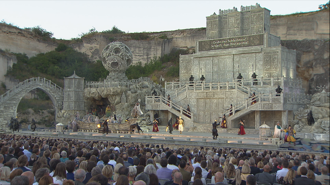Das Bühnenbild von Turandot im Steinbruch wirkt wie in Stein gehauen, davor das Publikum 