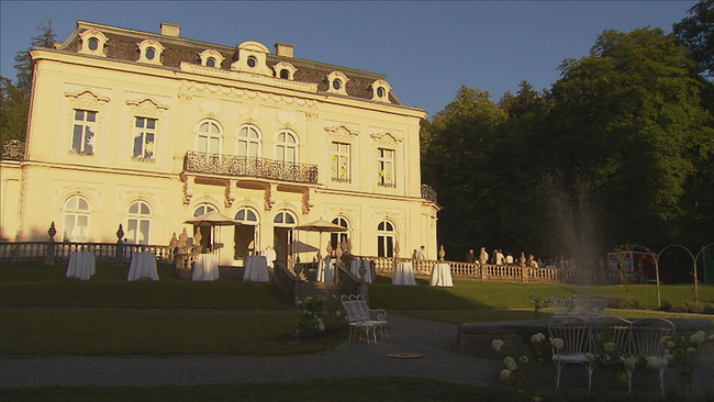 Villa Raczynski von außen, davor paar Stühle und Sessel, sowie ein Springbrunnen 