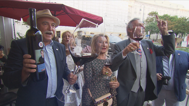 Willi Opitz hält überdimensionales Weinglas, Brigitta Wolf und Kurt Tiroch singen und halten Rotwein Gläser