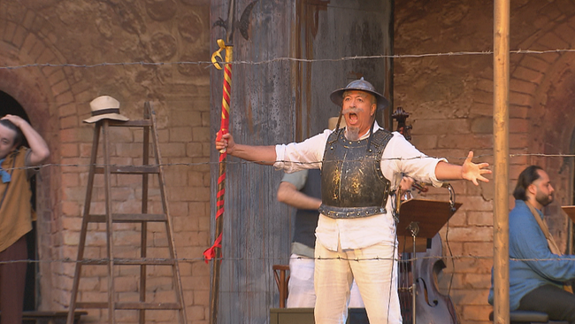 Lippert im Kostüm als Don Quichote singt mit geöffneten Armen und weit geöffnetem Mund