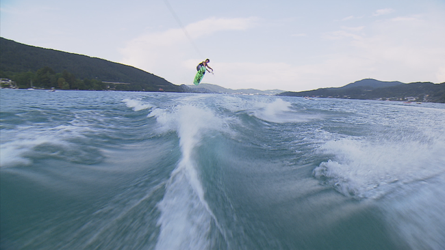 Wakeboarder springt über eine Welle und erweckt im Bild den Eindruck zu fliegen 