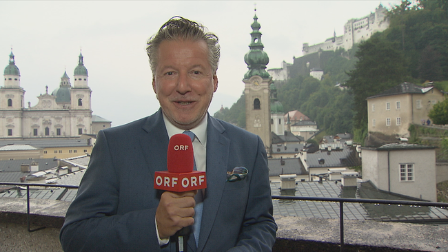 Christian Reichhold vor der Kulisse Salzburgs mit Mikrofon