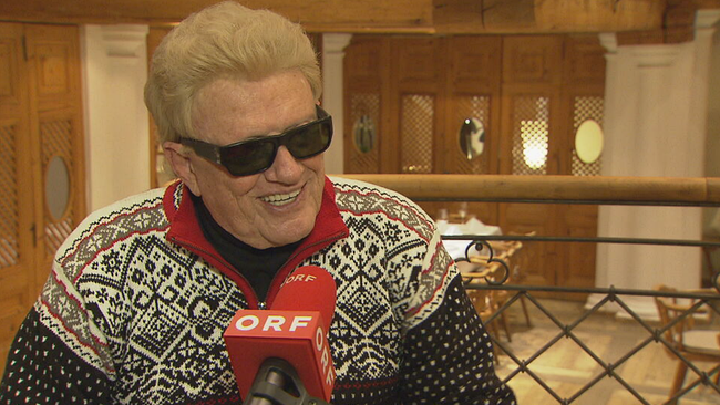 Heino lachend im Interview mit Sonnenbrille und winterlichem Pullover