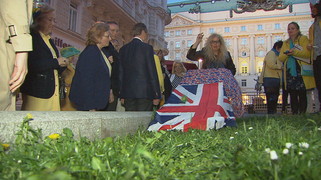 © ORF2/Seitenblicke Von unten gefilmt: Gras, darauf eine Rampe mit der Flagge abgehangen, darüber kugelt ein grünes Ei, Frau noch in Wurfgeste am Anfang der Rampe