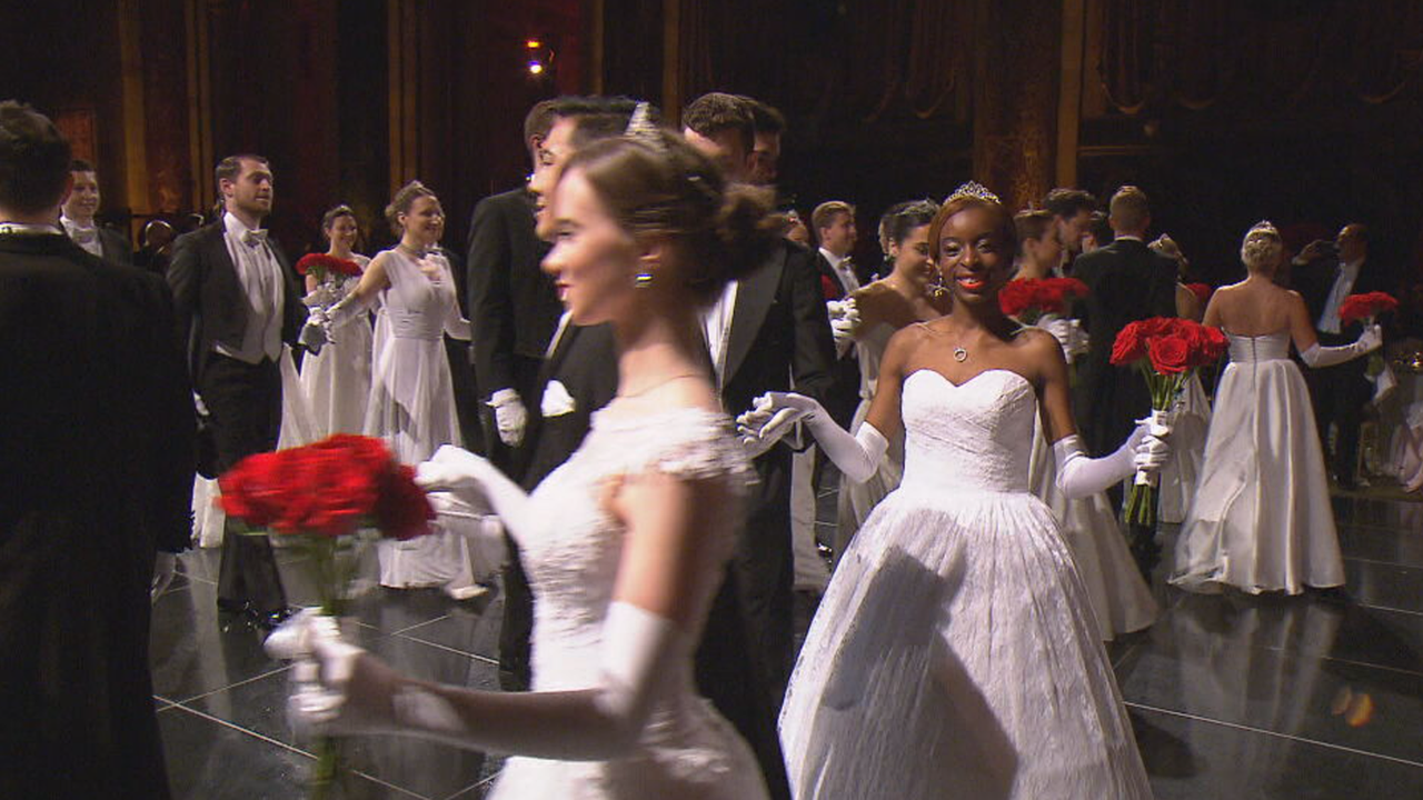 Debütantinnen in weißem Kleid mit Blumen in der Hand im Ballsaal 