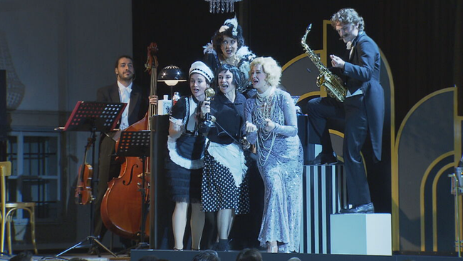 Ensemble in 20er Jahre Kostüm singt, Trompete und Kontrabass im Hintergrund