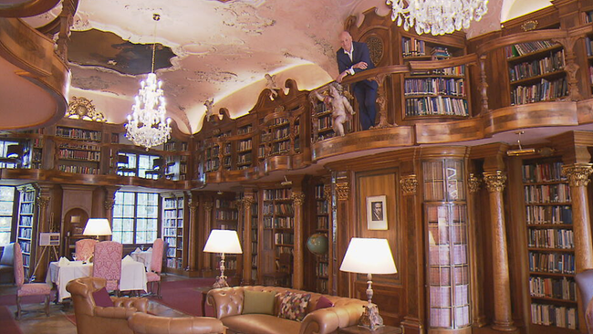 riesige alte Bibliothek, Weiss steht auf einem hölzernen Balkon, der über eine versteckte Wendeltreppe zu erreichen ist 