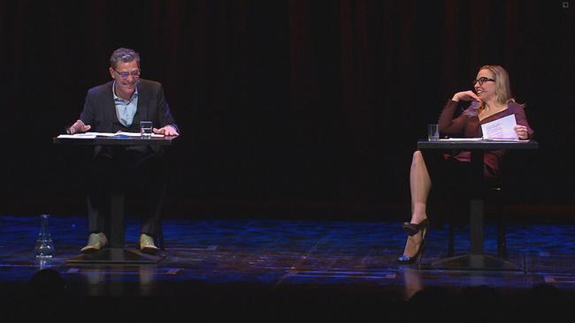 Nina Proll und Gregor Bloéb sitzen auf der Bühne hinter zwei Tischen und lachen