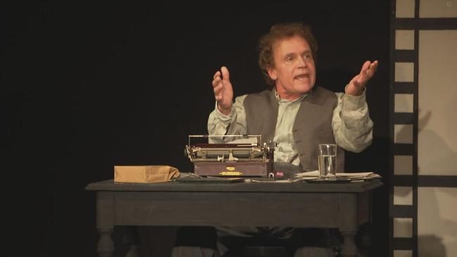 Alexander Wussow als Chaplin auf der Bühne. Er sitzt an einem Tisch, auf dem eine Schreibmaschine steht