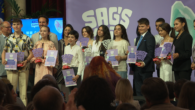 Eine Gruppe von Kindern und Jugendlichen, von denen alle eine Trophäe in der Hand halten, steht auf einer Bühne.