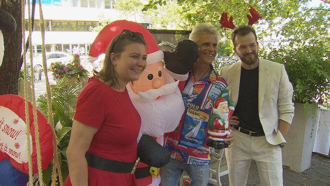 Julia Sobieszek, Thomas Brezina und Jan Frankl posieren in Weihnachtskostümen nebem einem Weihnachtsmann für die Kamera 