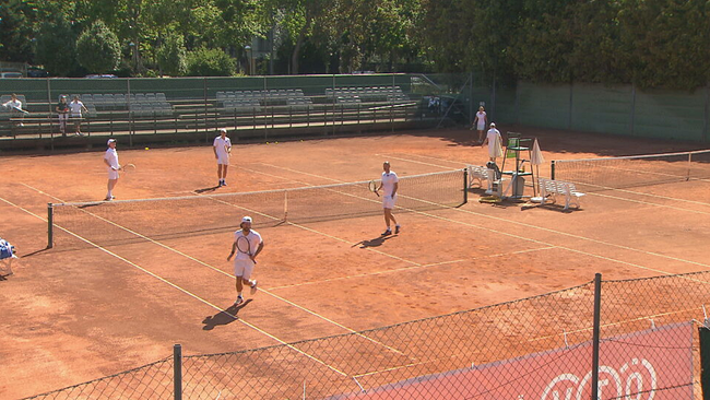 Vier Spieler bei einem Doppel-Tennis-Match auf dem Sandplatz von im Wiener Park Club 